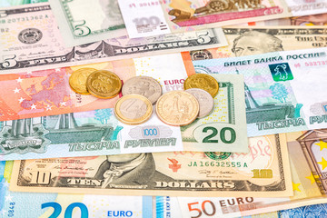 Different coins lying over different currency banknotes euro, dollars and rubles close up. Money background