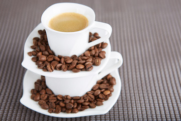 An espresso cup surrounded by coffee beans. 