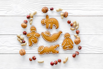 Healthy food for sportsman. Cookies in shape of yoga asanas near nuts on white wooden background top view copyspace
