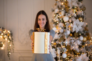 Cute girl next to the Christmas tree and gifts