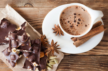 Coffee break with tasty dark chocolate and hazelnuts on a rustic table in kitchen