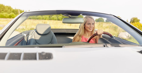 happy young woman driving convertible car