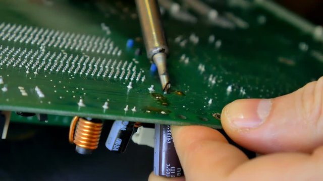 Electronics Engineer is Soldering an Electric Board repair computer.