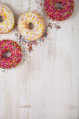 Multicolored donuts  on a wooden background.