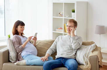 husband and pregnant wife with smartphone at home