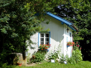 Holzhaus weiß blau romantisch mit Brunnen in Natur Garten Polen Masuren mit Blumen