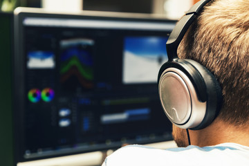 Obraz premium man doing video editing on computer with headphones on