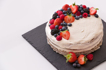 Top view on homemade vanilla birthday cake decorated with berries: strawberries, blueberries,...