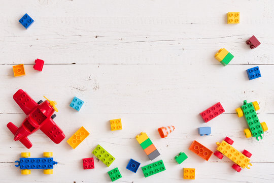 Top view on multi-color toy bricks on white wooden background. Toys in the table.