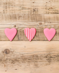 Top view on three little gingerbread cookies in hearts shape on retro wooden background. Flay layout. Love, Valentines's day concept