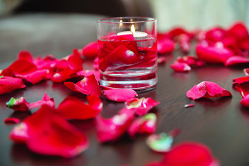 Fototapeta na wymiar Flower petals, candles and glass