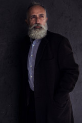 Pensive bearded man looking somewhere while posing in dark studio