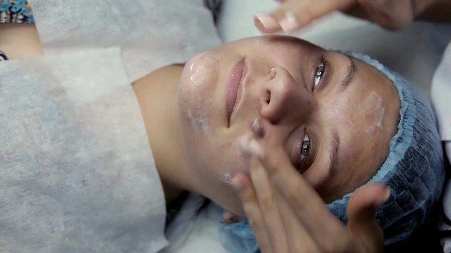 Beautician handles cream a client's face after lifting alginate mask