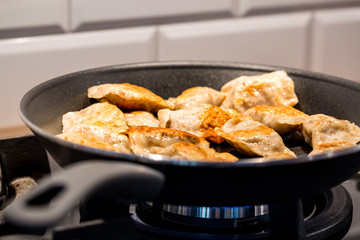 Traditional delicious Polish dumplings fried in a pan. Photography with shallow depth of field.