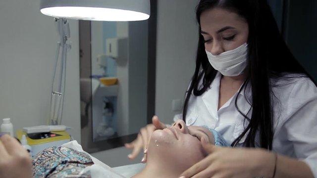 Beautician handles cream a client's face after lifting alginate mask
