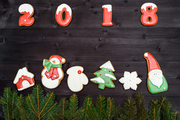 Happy new year 2018 sign symbol from red and white gingerbread cookies on dark wooden background, copy space. Top view, flat lay. Christmas cookies and fir tree branches border, free space