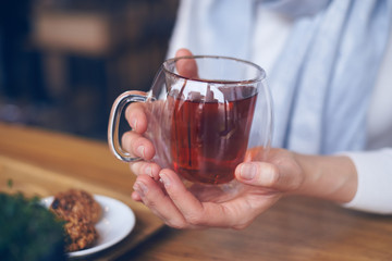 Hands of woman holding hot cup of tea to warm hands
