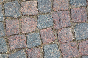 cobblestone pavement. Texture of cobblestone road close-up. Part of the road paved with red  black granite.