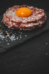  Raw ground meat with egg on a dark background, top view with copy space