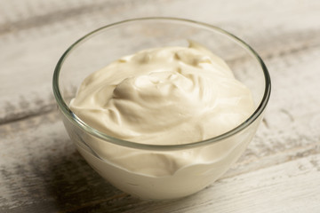 Glass bowl of homemade fruit yogurt on white wooden rustic table, toned