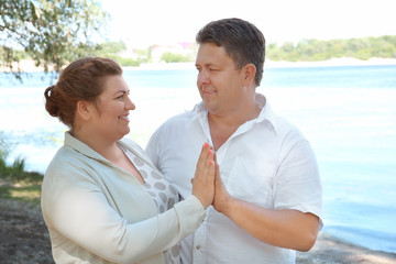Overweight couple near river on sunny day