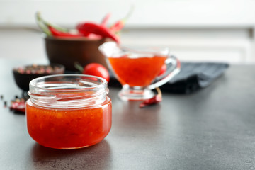 Composition with chili sauce in jar on table