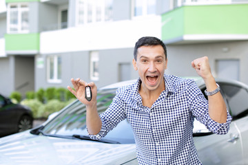 Happy man with key standing near new car