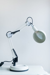 Lamp on a night table next to a bed.