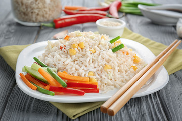 Plate with brown rice and vegetables on table