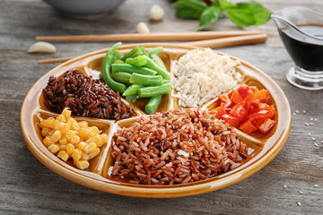Plate with brown rice and vegetables on wooden table