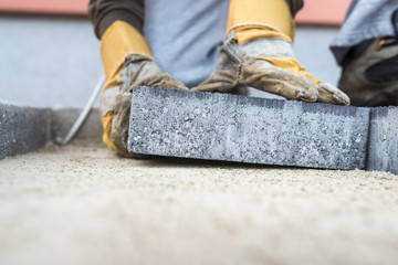 Building contractor laying a paving slab