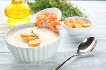 Tasty cream soup with shrimps in bowl on table