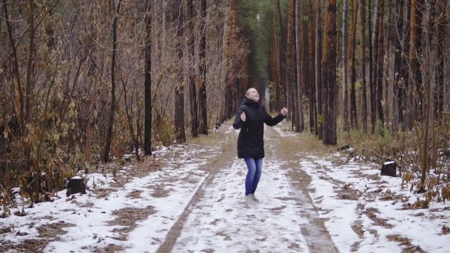girl jumping in the forest in slow motion. enjoys the first snow of the year. autumn forest