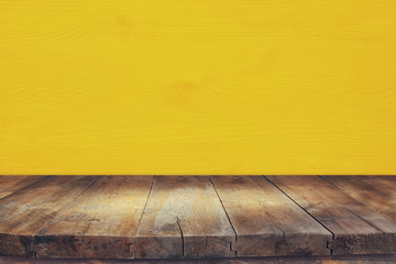 Empty table in front of yellow wooden background. For product display montage