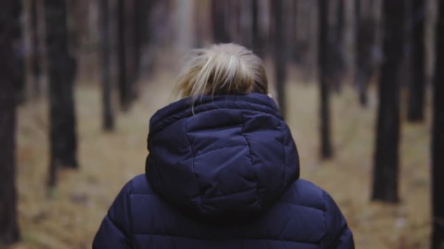 cinematic shot, slow motion. the girl is walking along the autumn forest in a jacket.