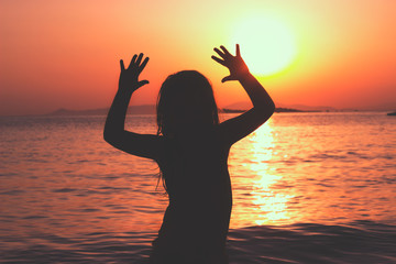 Fototapeta premium Silhouette of a little girl on the beach, sunset behind her