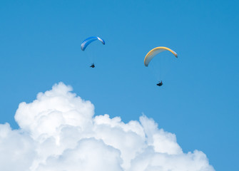 Two paragliders flying in the blue sky against the background of clouds. Paragliding in the sky on a sunny day.