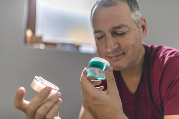 Mature Man Smelling Cosmetic Product