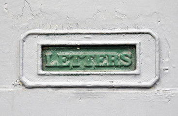 green painter mailbox in a grey house door with the word letters cast in the metal