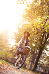 Happy woman riding bike bicycle in fall autumn park