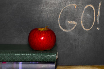 Education concept with apple on stack of books on blackboard background