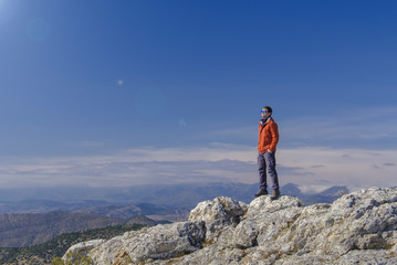 Man standing at the peak of rock mountain. Daylight