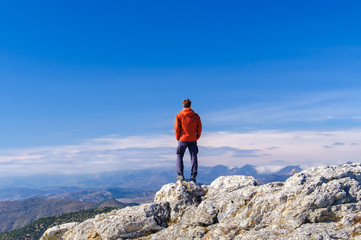 Obraz premium Man standing at the peak of rock mountain. Daylight