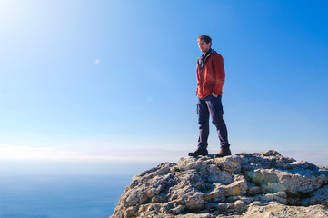 Obraz premium Man standing at the peak of rock mountain. Daylight