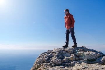 Obraz premium Smiling man in sunglasses standing at the peak of rock mountain. Daylight