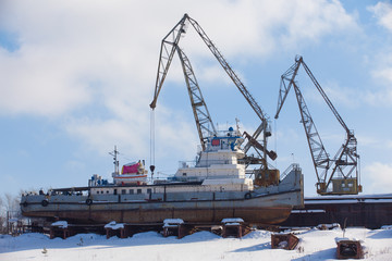 Fototapeta premium two cranes and cargo ship in winter backwater