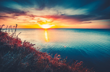Obrazy na Szkle  Zachód słońca na tle nieba. Naturalny zachód słońca wschód słońca nad oceanem. Jasne Dramatyczne Niebo I Błękitna Woda. Kolorowy krajobraz przyrody