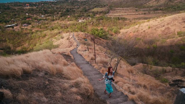 Young caucasian woman walking up to Pura Batu Korsi hill temple. Shot in Pemuteran, Bali, Indonesia.