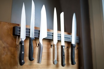 Set of kitchen knives hanging on the wall - Powered by Adobe