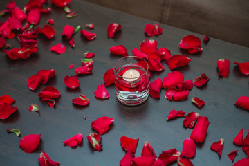 Beautiful romantic red candles with flower petals. Flower petals, candles and glass .